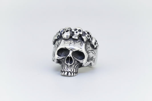 Silver skull ring with small skulls on a light background